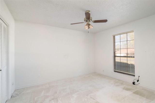 empty room featuring a textured ceiling, light carpet, and ceiling fan