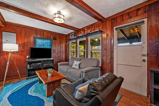 living room featuring hardwood / wood-style floors, a textured ceiling, wooden walls, and beamed ceiling