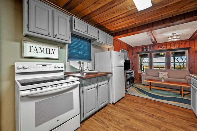 kitchen featuring light hardwood / wood-style flooring, gray cabinetry, white appliances, and wood walls