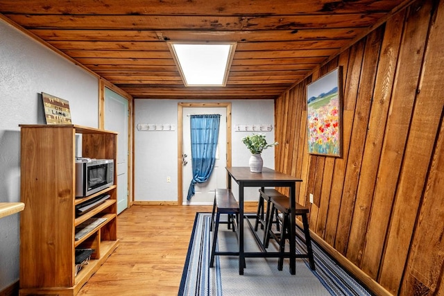 dining room with wood ceiling, wooden walls, and light wood-type flooring