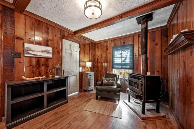 kitchen with wood walls, sink, light hardwood / wood-style floors, a textured ceiling, and beam ceiling