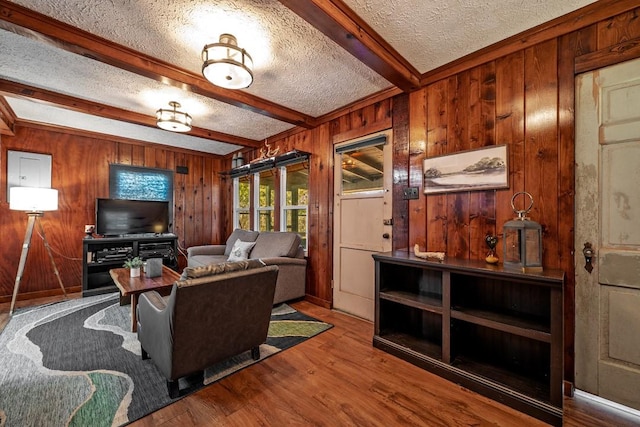 living room with beamed ceiling, wooden walls, hardwood / wood-style floors, and a textured ceiling