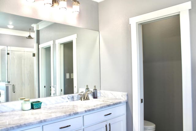 bathroom with vanity, toilet, a shower with door, and ornamental molding