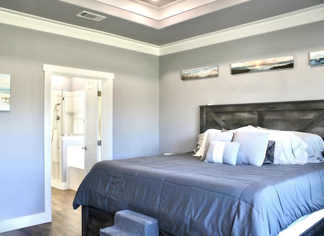 bedroom featuring visible vents, wood finished floors, baseboards, connected bathroom, and ornamental molding