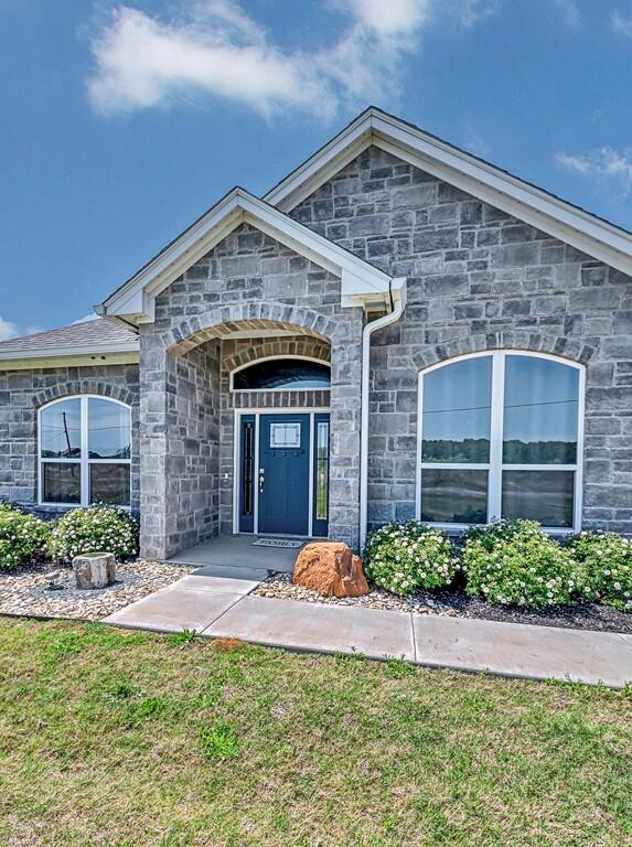 property entrance featuring a yard and stone siding