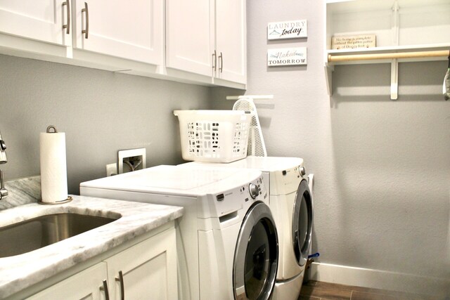 laundry area featuring washing machine and clothes dryer, wood finished floors, cabinet space, a sink, and baseboards