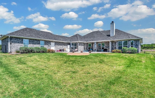 rear view of property with fence, a chimney, a lawn, and a patio area