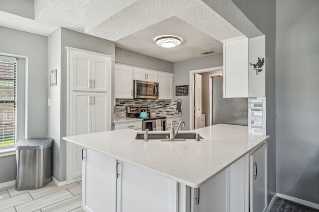 kitchen with backsplash, white cabinets, sink, kitchen peninsula, and stainless steel appliances