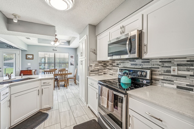 kitchen with sink, decorative backsplash, ceiling fan, appliances with stainless steel finishes, and white cabinetry