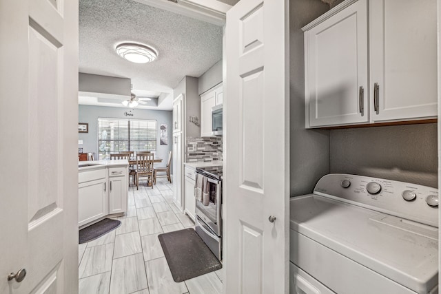 kitchen with white cabinets, decorative backsplash, appliances with stainless steel finishes, and washer / clothes dryer