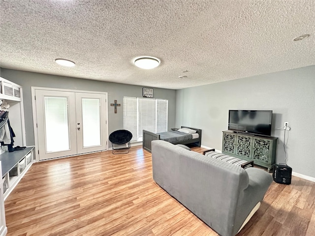 living room featuring a textured ceiling, light hardwood / wood-style flooring, and french doors