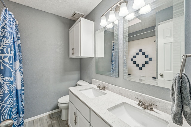 bathroom with walk in shower, wood-type flooring, a textured ceiling, toilet, and vanity