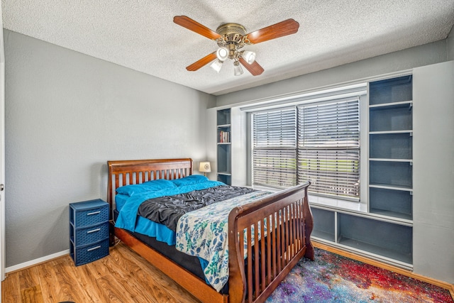 bedroom with hardwood / wood-style floors, a textured ceiling, and ceiling fan