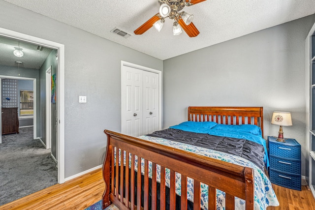 bedroom with wood-type flooring, a textured ceiling, a closet, and ceiling fan