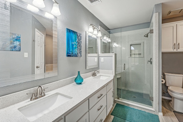 bathroom with a shower with door, vanity, hardwood / wood-style floors, and toilet