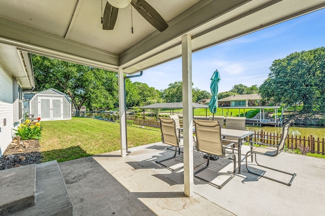 view of patio / terrace with ceiling fan, a water view, and a storage shed