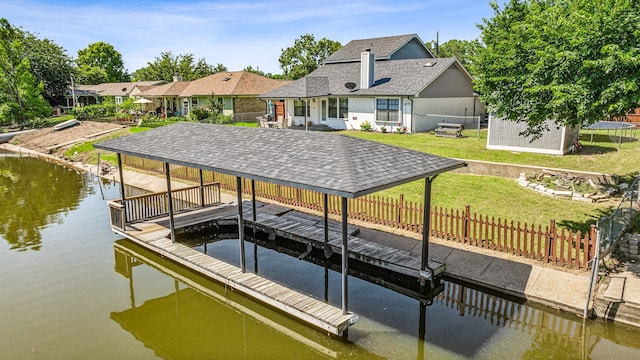 view of dock with a lawn and a water view