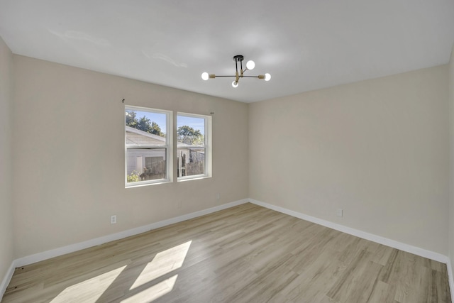 empty room with light wood-type flooring and an inviting chandelier