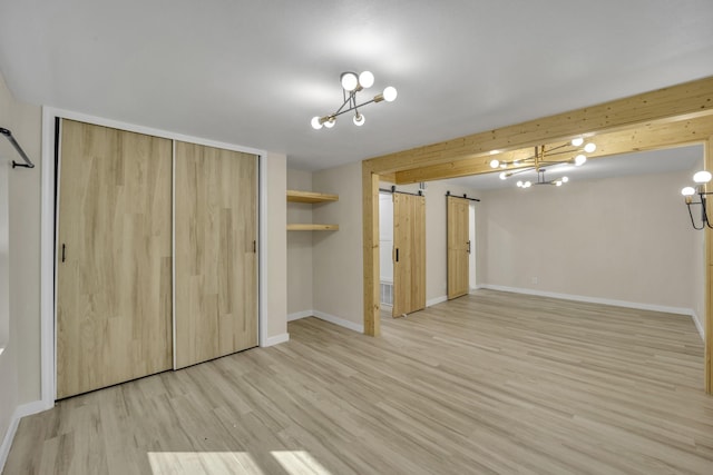 unfurnished bedroom featuring light wood-type flooring, a barn door, and a closet