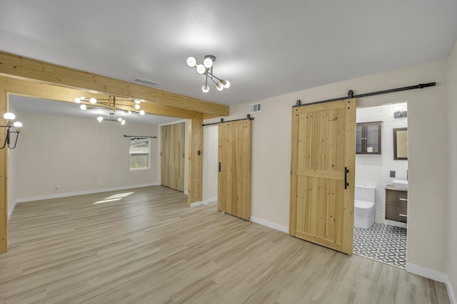 unfurnished room with a barn door and light wood-type flooring