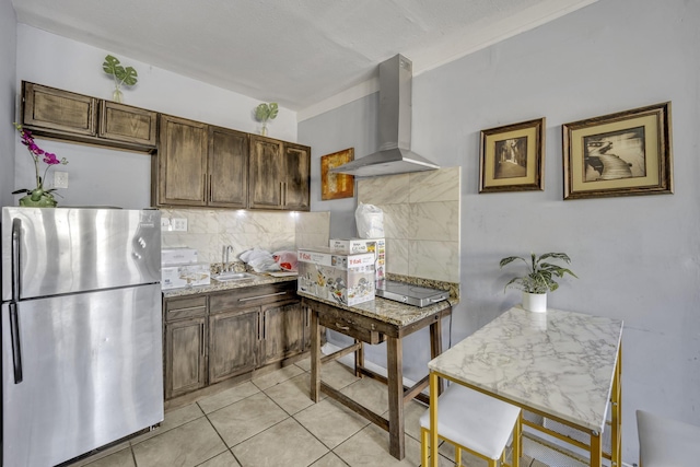 kitchen with stainless steel refrigerator, sink, wall chimney range hood, tasteful backsplash, and light tile patterned flooring