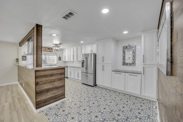 kitchen with backsplash, white cabinets, a textured ceiling, kitchen peninsula, and stainless steel appliances