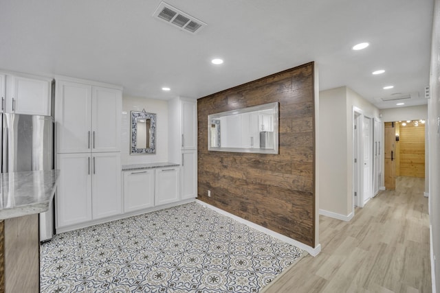 kitchen featuring wooden walls, white cabinetry, and stainless steel refrigerator