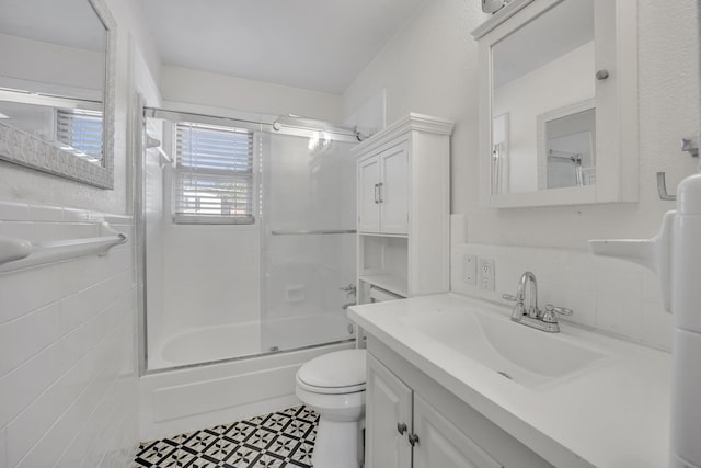 full bathroom featuring vanity, tile patterned floors, bath / shower combo with glass door, toilet, and tile walls