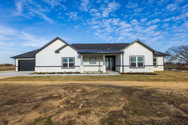 modern farmhouse with a porch, a garage, and a front lawn