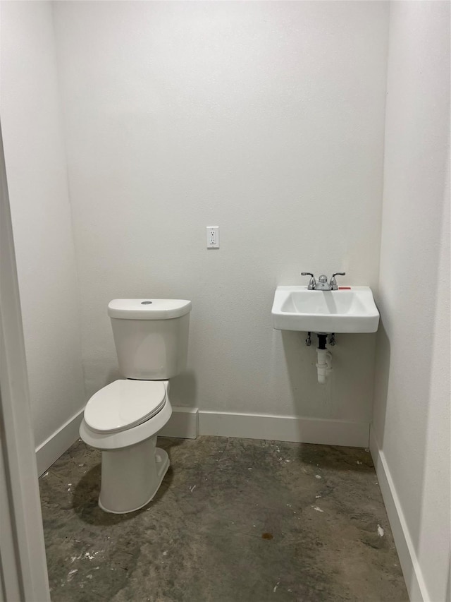 bathroom with sink, concrete flooring, and toilet