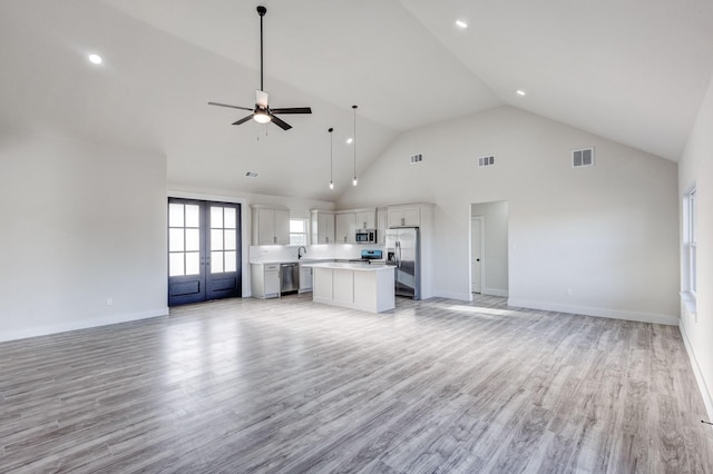 unfurnished living room featuring ceiling fan, light hardwood / wood-style floors, high vaulted ceiling, and french doors