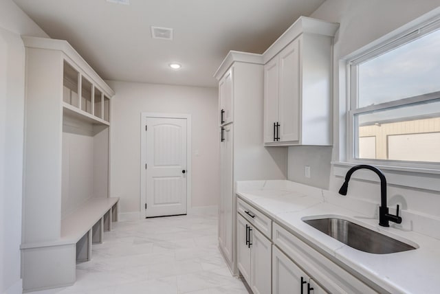 kitchen featuring white cabinets, light stone countertops, and sink