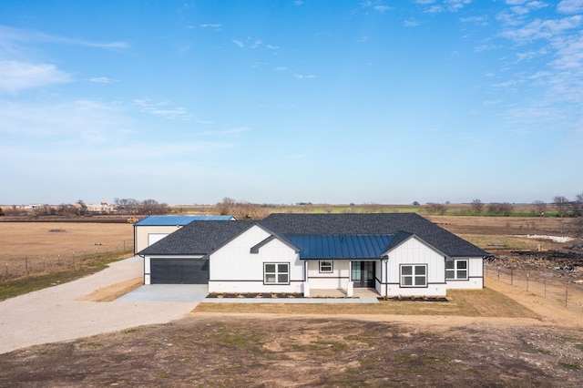 modern inspired farmhouse featuring covered porch, a rural view, and a garage