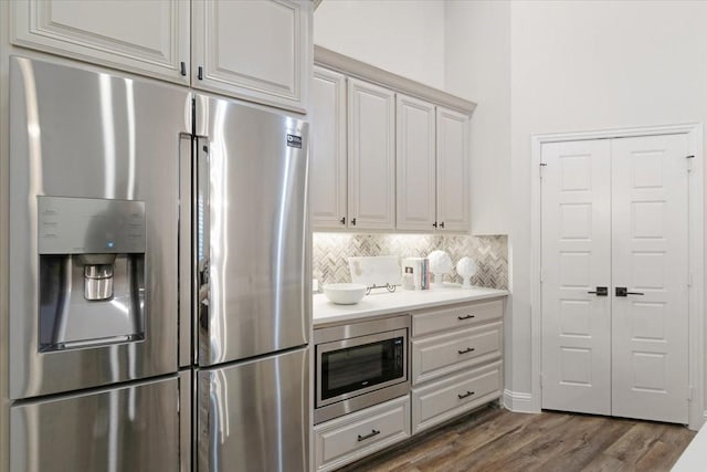 kitchen featuring tasteful backsplash, stainless steel appliances, dark hardwood / wood-style floors, and white cabinets