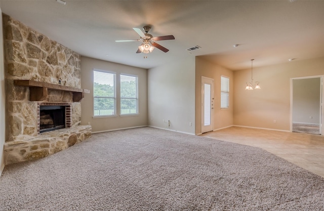 unfurnished living room featuring ceiling fan with notable chandelier, a stone fireplace, and light tile patterned floors