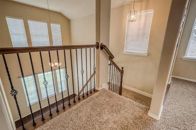 staircase with carpet, vaulted ceiling, and an inviting chandelier