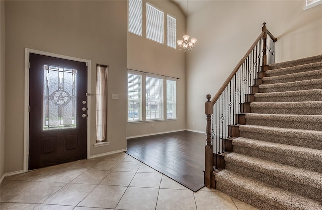 tiled entrance foyer with a healthy amount of sunlight, a high ceiling, and an inviting chandelier