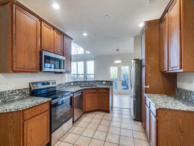 kitchen with appliances with stainless steel finishes, french doors, light stone counters, sink, and light tile patterned floors