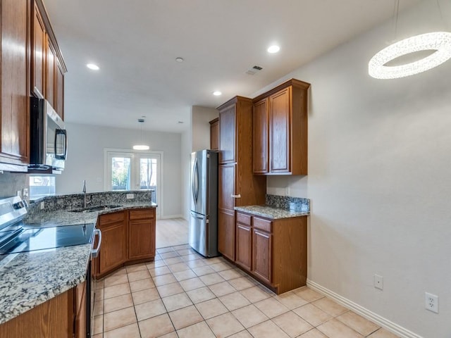 kitchen with stone counters, light tile patterned flooring, stainless steel appliances, and decorative light fixtures