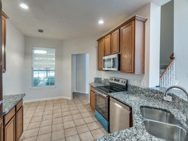 kitchen with light stone counters, sink, light tile patterned floors, and stainless steel appliances