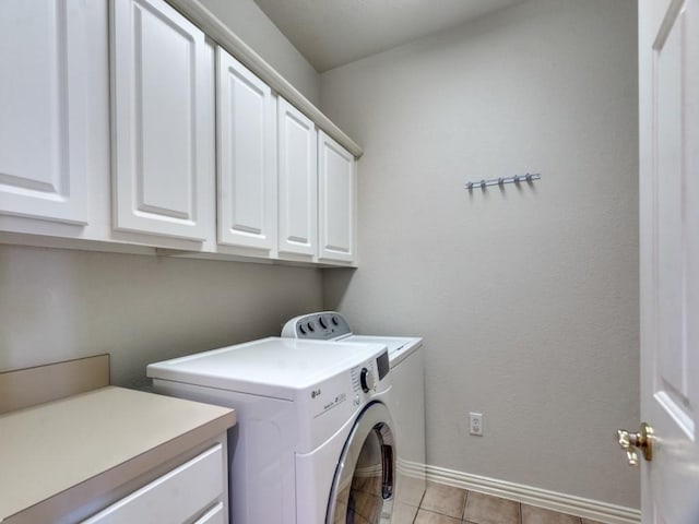 clothes washing area featuring washer and clothes dryer, light tile patterned floors, and cabinets