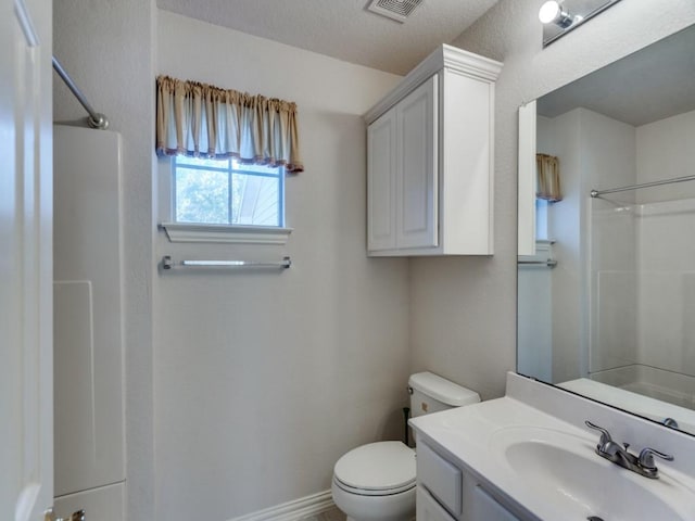 bathroom with walk in shower, vanity, and toilet