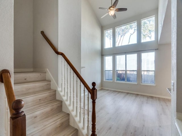 stairs featuring hardwood / wood-style floors, ceiling fan, and a high ceiling