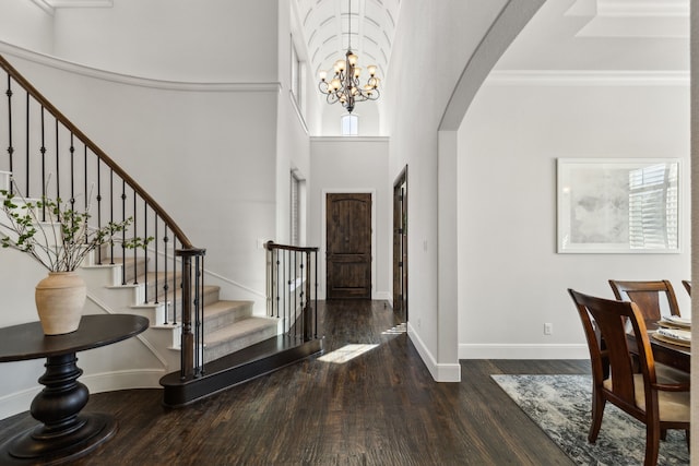 foyer entrance featuring a high ceiling, an inviting chandelier, crown molding, and dark hardwood / wood-style floors