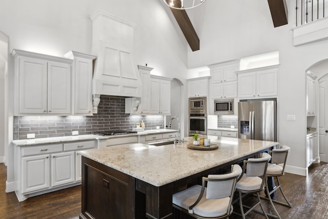 kitchen featuring appliances with stainless steel finishes, high vaulted ceiling, beam ceiling, white cabinetry, and sink