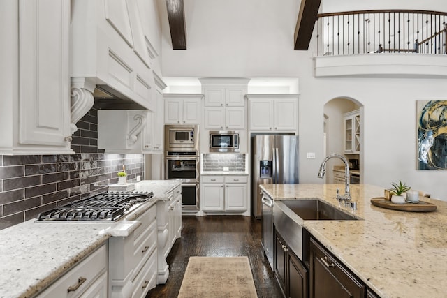 kitchen featuring stainless steel appliances, white cabinets, light stone countertops, dark hardwood / wood-style flooring, and beam ceiling