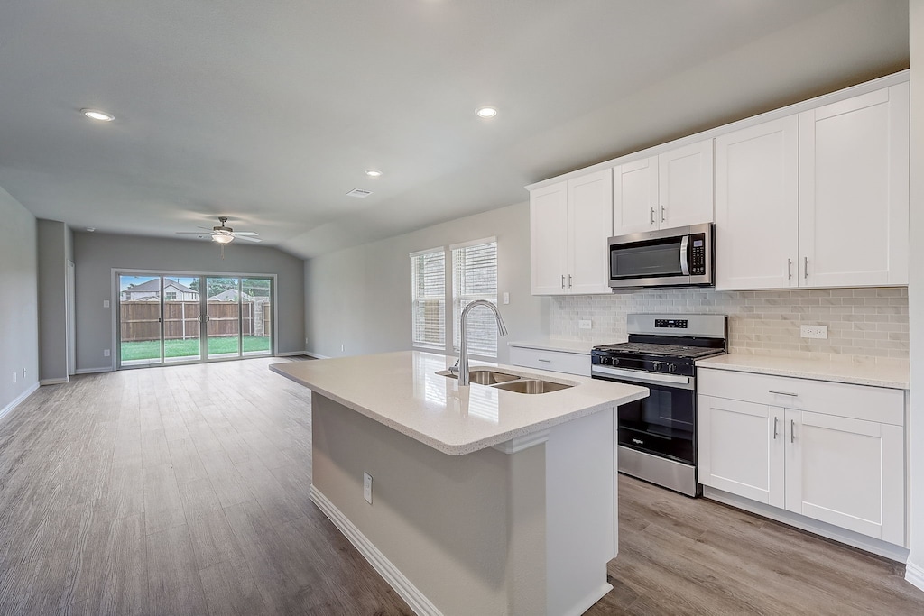 kitchen with a kitchen island with sink, sink, white cabinets, and appliances with stainless steel finishes