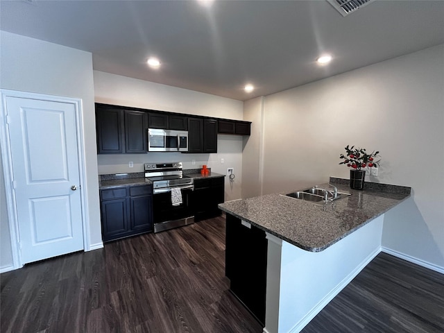 kitchen with kitchen peninsula, a breakfast bar area, appliances with stainless steel finishes, dark hardwood / wood-style floors, and sink