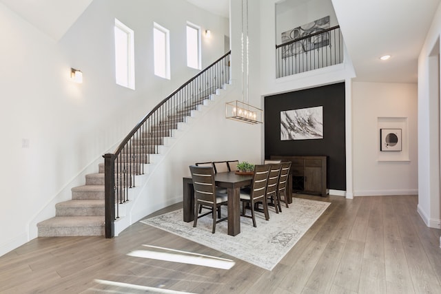 dining area with hardwood / wood-style flooring, a towering ceiling, and a notable chandelier