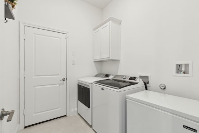 washroom featuring washer and dryer, cabinets, and light tile patterned floors